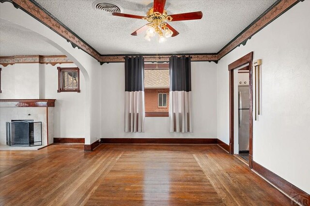423 Washington St, Pueblo, CO 81004 - unfurnished living room featuring a textured ceiling, wood-type flooring, arched walkways, a ceiling fan, and baseboards