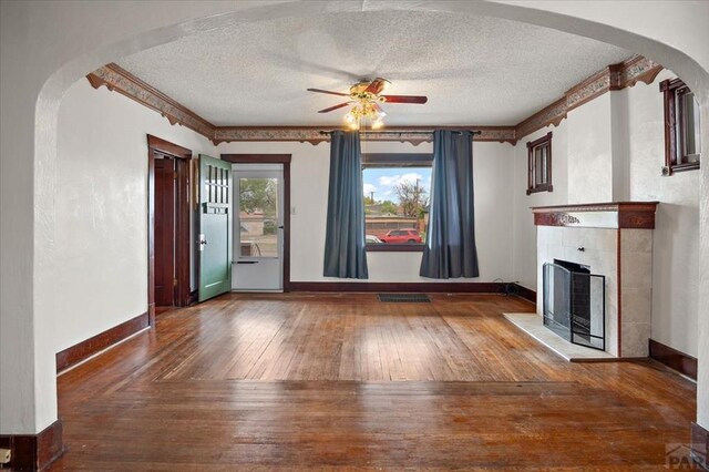 423 Washington St, Pueblo, CO 81004 - unfurnished living room with a ceiling fan, wood-type flooring, a textured ceiling, baseboards, and a tiled fireplace