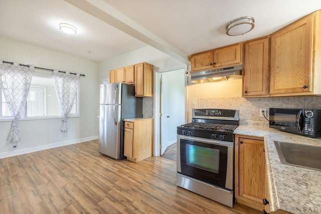 212 W Summit Ave, Pueblo, CO 81004 - kitchen with under cabinet range hood, stainless steel appliances, light wood-type flooring, and tasteful backsplash