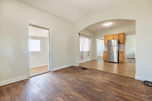 212 W Summit Ave, Pueblo, CO 81004 - kitchen featuring freestanding refrigerator, arched walkways, plenty of natural light, and dark wood-style floors