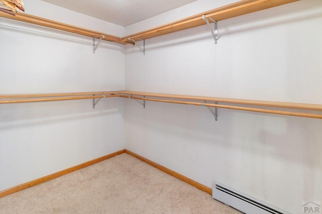 spacious closet featuring a baseboard heating unit and light carpet