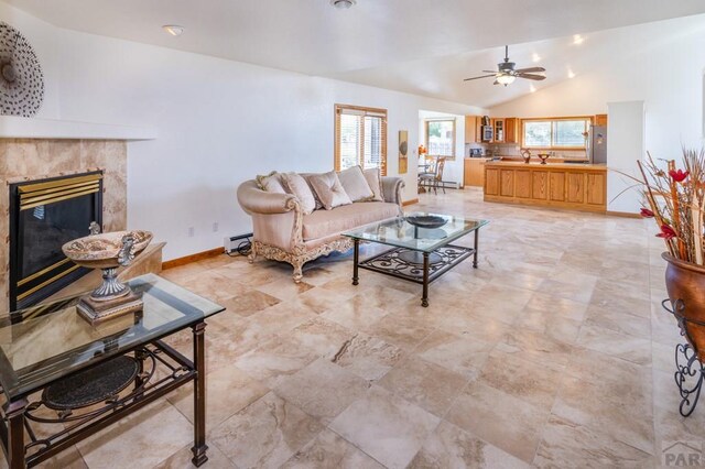 living area with baseboards, vaulted ceiling, baseboard heating, and a premium fireplace