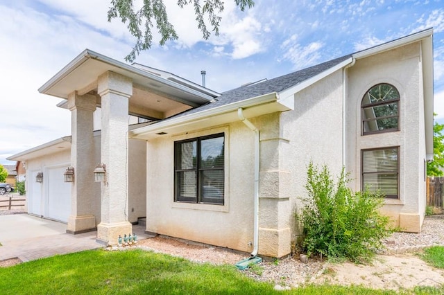 exterior space featuring an attached garage, a lawn, and stucco siding