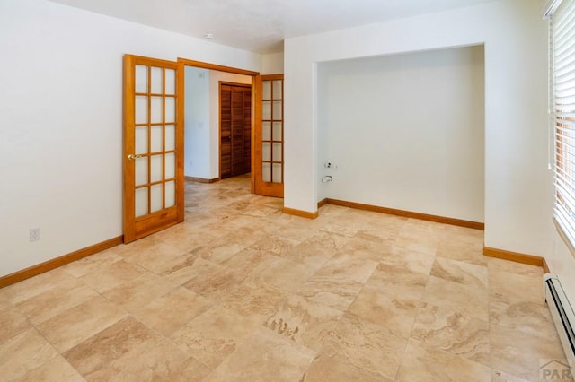 unfurnished room featuring french doors, baseboard heating, and baseboards