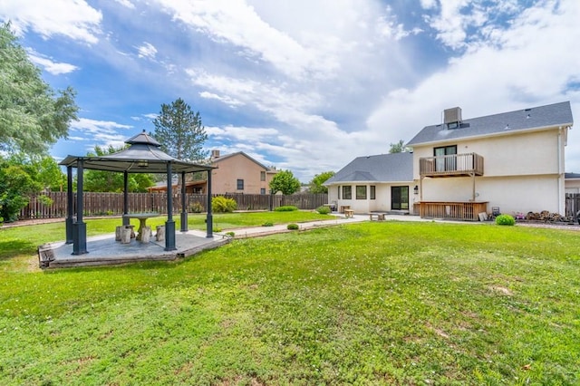 back of house featuring a lawn, a balcony, a fenced backyard, a gazebo, and a patio area