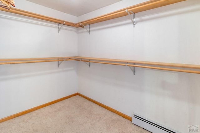 spacious closet featuring a baseboard heating unit and light colored carpet