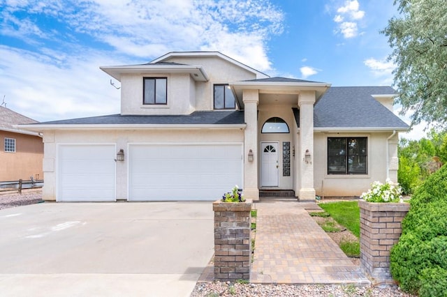 view of front facade with a garage, driveway, a shingled roof, and stucco siding