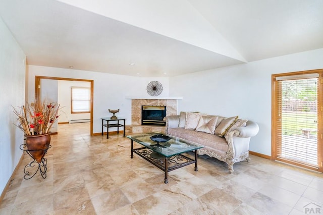 living area with a baseboard radiator, vaulted ceiling, baseboards, and a premium fireplace