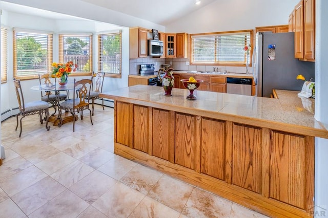 kitchen featuring brown cabinetry, glass insert cabinets, a peninsula, vaulted ceiling, and stainless steel appliances