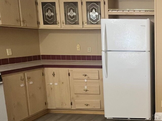 kitchen with cream cabinets, glass insert cabinets, and freestanding refrigerator