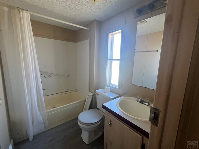 bathroom with toilet, wood finished floors, shower / bathtub combination with curtain, a textured ceiling, and vanity