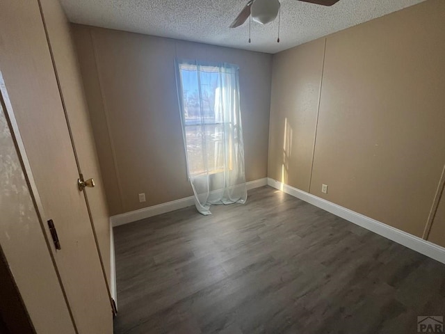 unfurnished bedroom with a textured ceiling, dark wood finished floors, a ceiling fan, and baseboards