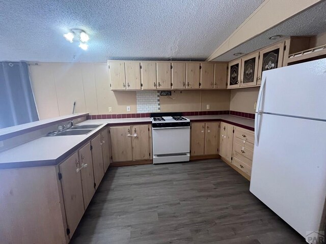 kitchen featuring a textured ceiling, white appliances, a sink, and glass insert cabinets