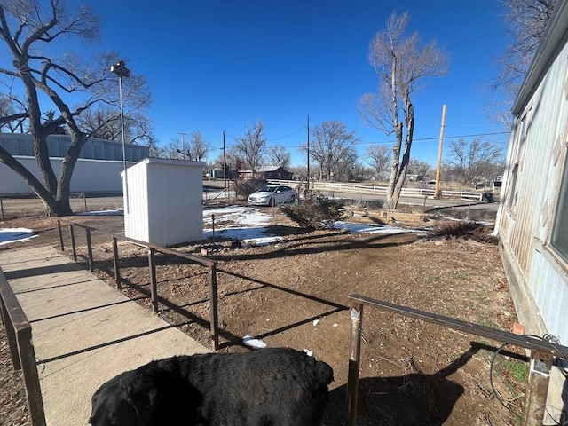 view of yard featuring an outdoor structure, fence, and a storage shed