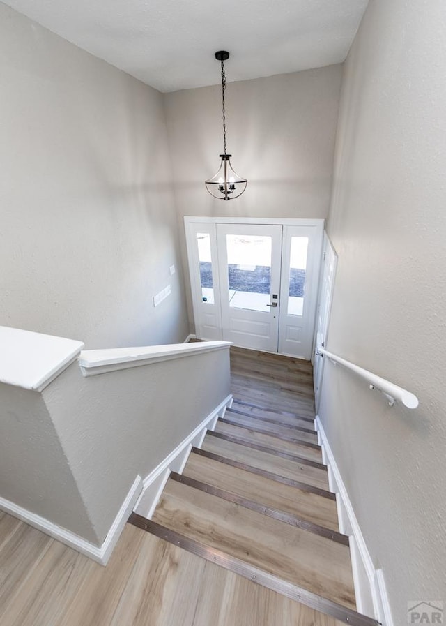 stairs with baseboards, a chandelier, and wood finished floors