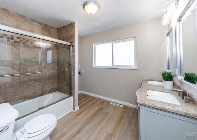 full bathroom with baseboards, visible vents, toilet, wood finished floors, and a sink