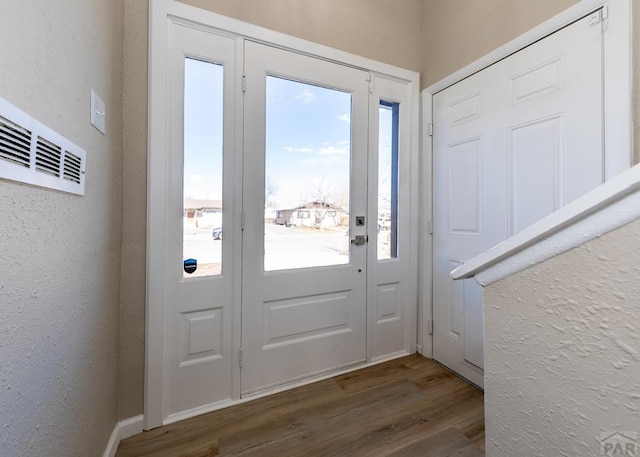 entryway with a wealth of natural light, a textured wall, and wood finished floors