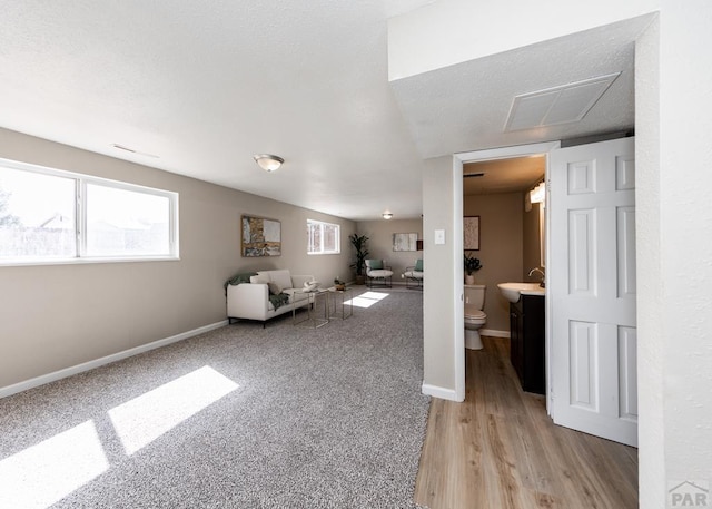 unfurnished living room with light wood-style floors, baseboards, visible vents, and light colored carpet