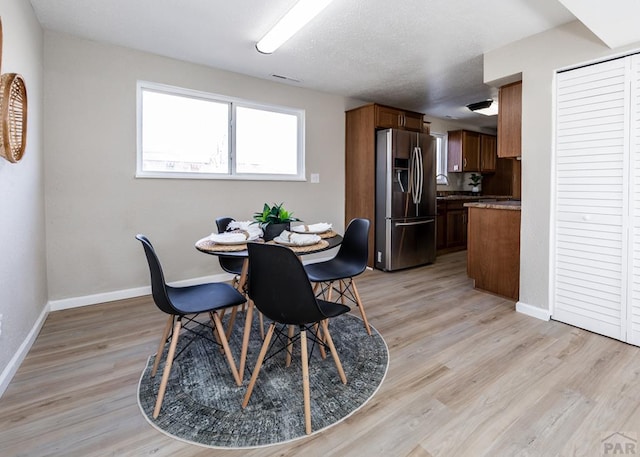 dining area with visible vents, baseboards, a textured ceiling, and light wood finished floors