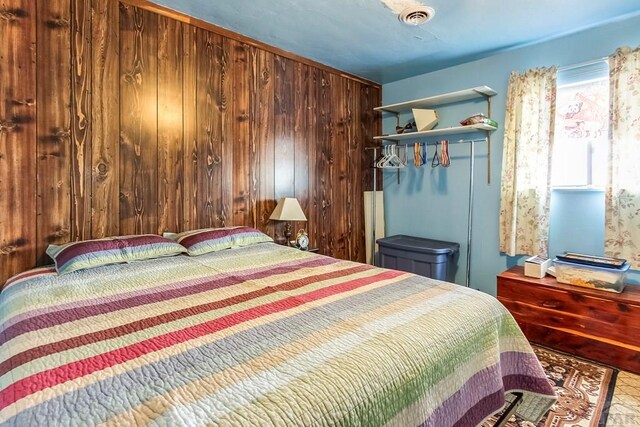 bedroom featuring a closet, visible vents, and wood walls