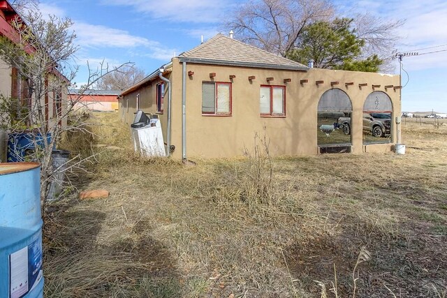 view of property exterior featuring roof with shingles and stucco siding