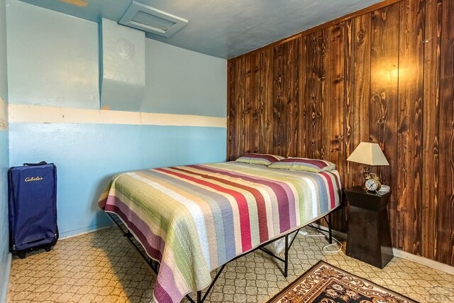 bedroom featuring attic access and wooden walls