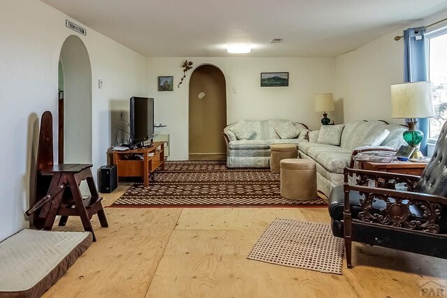 living area featuring visible vents, arched walkways, and wood finished floors