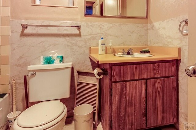 bathroom featuring tile walls, a wainscoted wall, vanity, and toilet