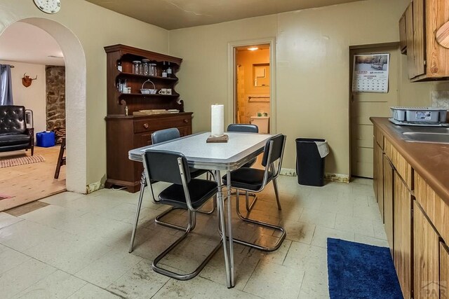 dining room featuring arched walkways, baseboards, and light floors