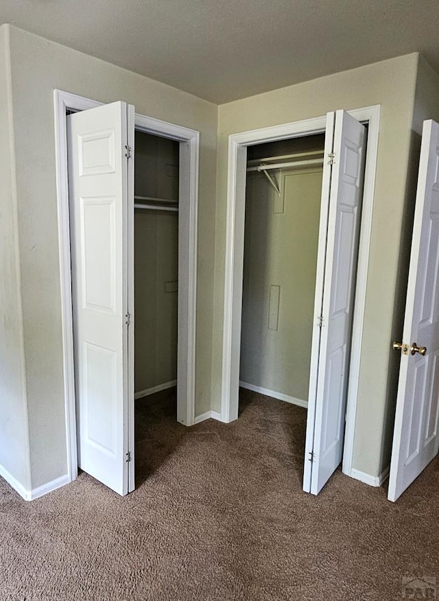 unfurnished bedroom with dark colored carpet and baseboards