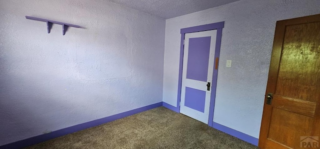 spare room with a textured ceiling, a textured wall, carpet flooring, and baseboards