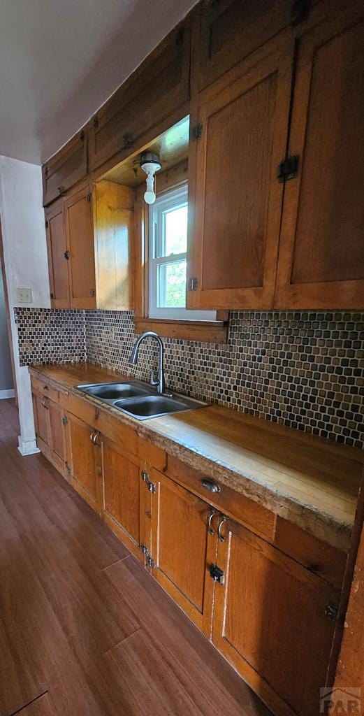 kitchen featuring decorative backsplash, brown cabinetry, a sink, and light countertops