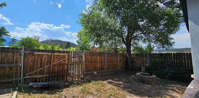 view of yard with an outdoor fire pit, a fenced backyard, and a gate