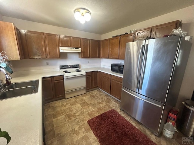 15840 Teak Pl, Elbert, CO 80106 - kitchen featuring white range with electric stovetop, black microwave, a sink, freestanding refrigerator, and under cabinet range hood