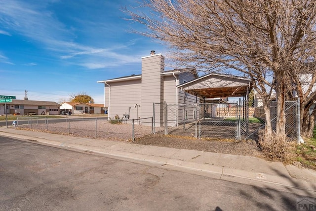 view of property exterior featuring driveway, a fenced front yard, and a chimney