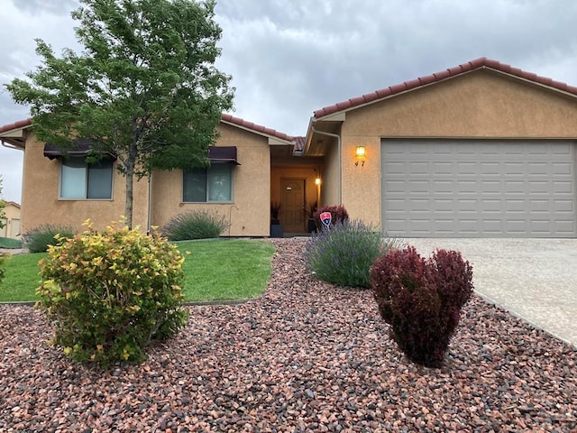 47 S Jibbsam Way, Pueblo West, CO 81007 - view of front of property featuring a tiled roof, stucco siding, driveway, a garage, and a front lawn