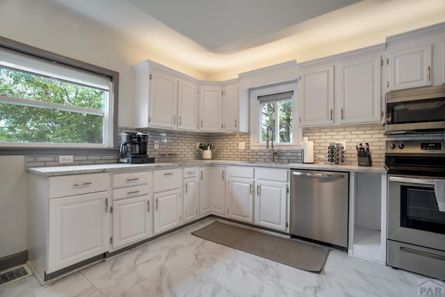 411 Olive St, Colorado Springs, CO 80904 - kitchen featuring stainless steel appliances, a sink, light marble finish flooring, backsplash, and white cabinets