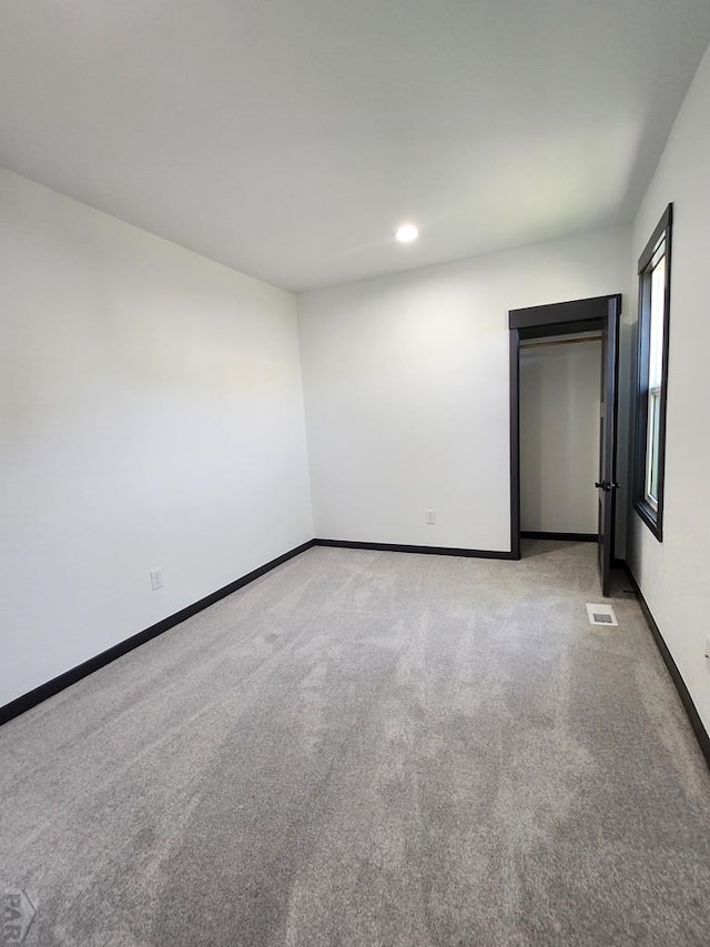 unfurnished bedroom featuring baseboards, visible vents, and light colored carpet