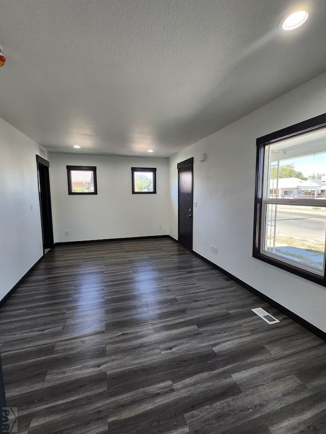 spare room with dark wood-style floors, a textured ceiling, and a wealth of natural light