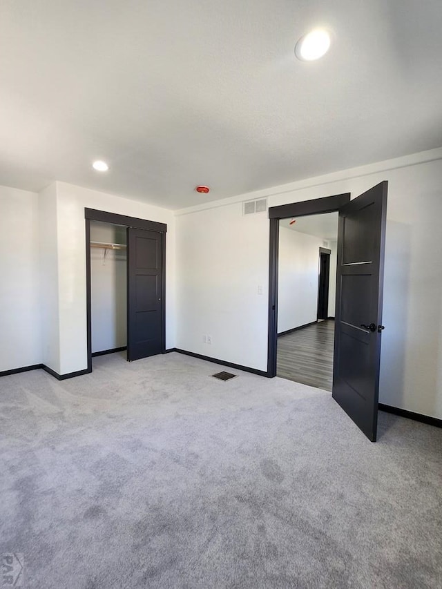 unfurnished bedroom with recessed lighting, light colored carpet, visible vents, baseboards, and a closet