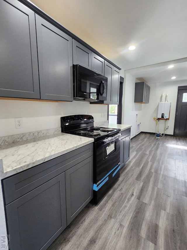 kitchen featuring gray cabinetry, recessed lighting, wood finished floors, baseboards, and black appliances