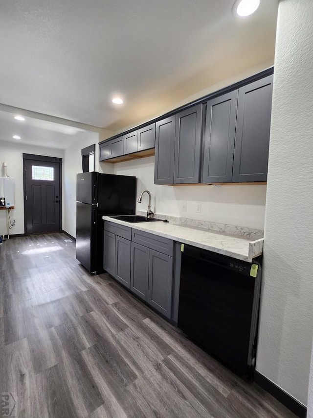 kitchen featuring dark wood finished floors, gray cabinets, light countertops, a sink, and black appliances