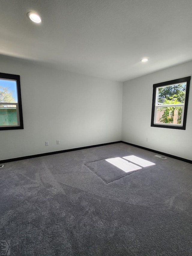 unfurnished room with carpet floors, recessed lighting, visible vents, and baseboards