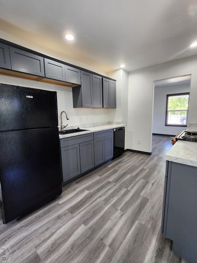 kitchen with black appliances, gray cabinets, light countertops, and a sink