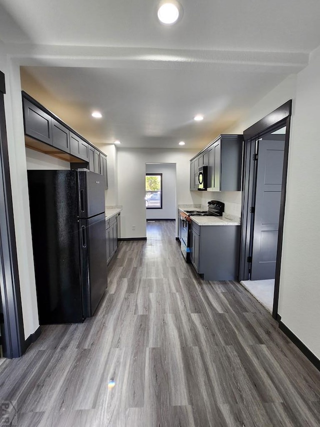 kitchen featuring dark wood-style floors, stove, stainless steel microwave, freestanding refrigerator, and gray cabinetry