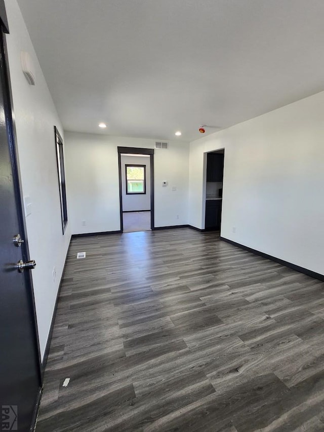 spare room featuring dark wood-style floors, recessed lighting, visible vents, and baseboards