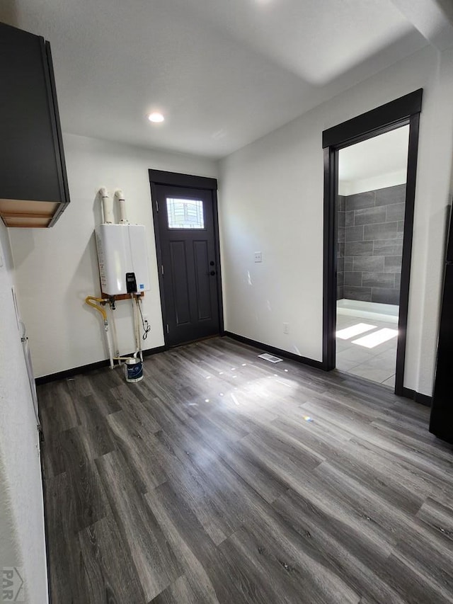 foyer with dark wood-style floors, baseboards, and tankless water heater