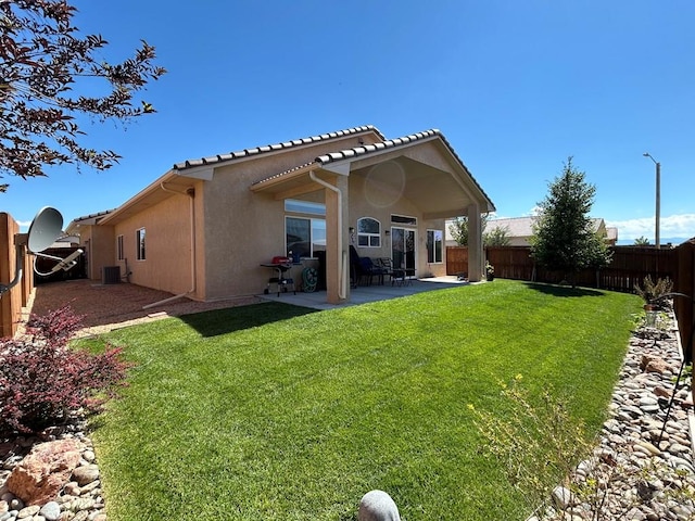 rear view of property featuring a yard, stucco siding, a patio area, cooling unit, and a fenced backyard