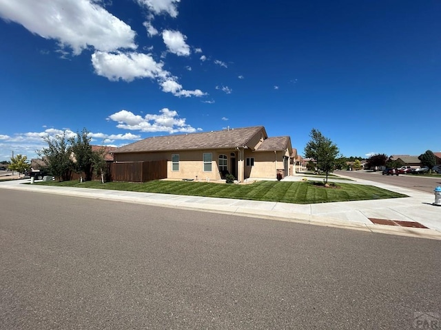 view of front of property featuring stucco siding, fence, and a front yard