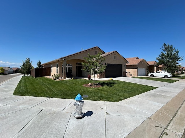 single story home with a garage, concrete driveway, stucco siding, fence, and a front yard